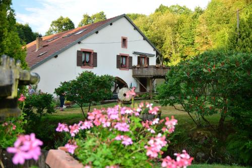 une maison blanche avec des fleurs roses devant elle dans l'établissement Vacance conviviales dans les Vosges 8 Gîtes, à Ban-de-Sapt