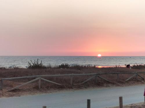 a sunset over the ocean with a wooden fence at Flamenco playa in El Puerto de Santa María