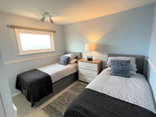 a bedroom with two beds and a window at 126 Hemsby Holiday Chalet, Convenient for sandy beach in Hemsby