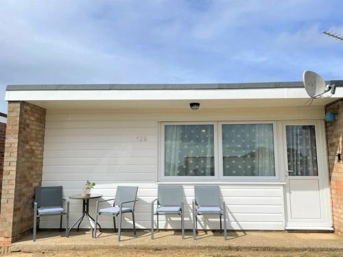 a group of chairs and a table in front of a garage at 126 Hemsby Holiday Chalet, Convenient for sandy beach in Hemsby