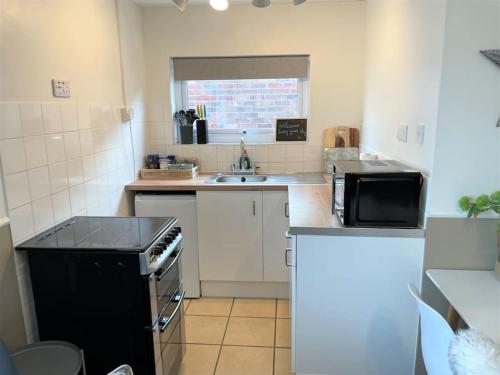 a small kitchen with a stove and a sink at 126 Hemsby Holiday Chalet, Convenient for sandy beach in Hemsby