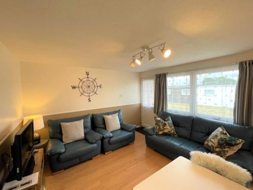 a living room with a couch and a tv at 126 Hemsby Holiday Chalet, Convenient for sandy beach in Hemsby