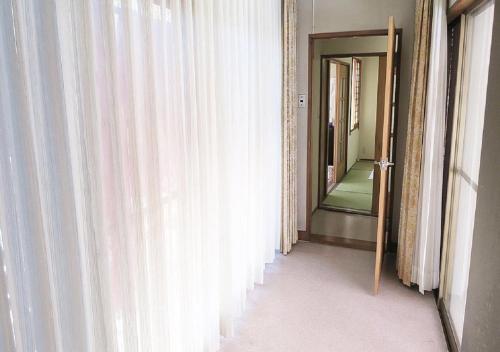 - un couloir avec des rideaux blancs et un miroir dans l'établissement 民宿みゆき, à Fujikawaguchiko