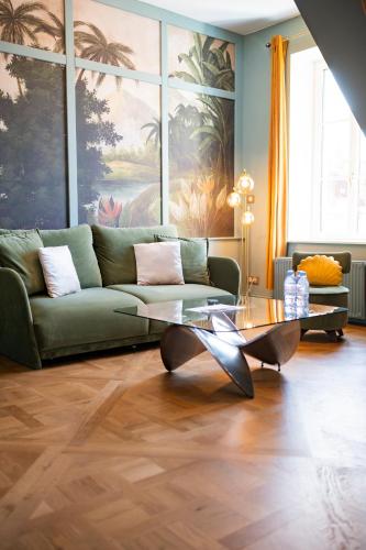 a living room with a green couch and a glass table at La Villa Ribière in Auxerre
