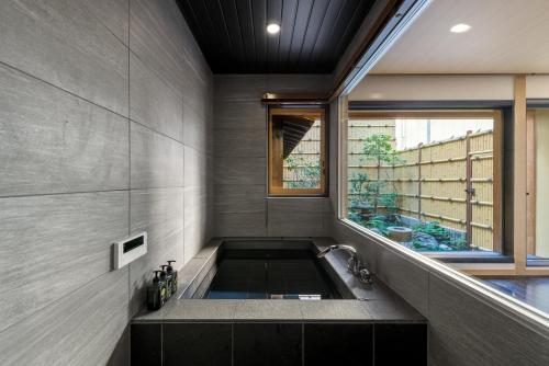 a bathroom with a bath tub with a window at Hanatoki Machiya House in Kyoto