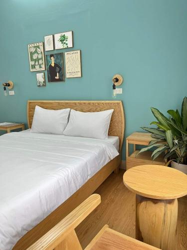 a bedroom with a bed and a table and a blue wall at Hidden Hue Homestay in Hue