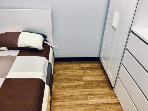 a small bedroom with a bed and wooden floors at condo-living at its best in Manila