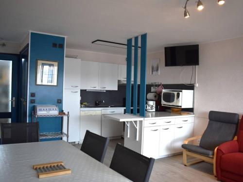 une cuisine avec des armoires blanches et une table avec des chaises dans l'établissement Appartement Spacieux 4 Pièces en Centre-Ville avec Cuisine Équipée et Chambres Confortables - FR-1-580-28, à Font-Romeu-Odeillo-Via