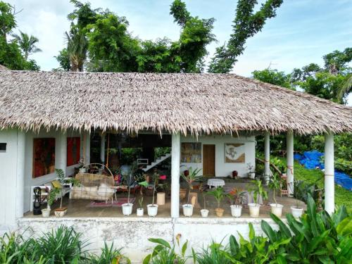 mały biały dom z dachem krytym strzechą w obiekcie The Living Room Siargao w mieście General Luna