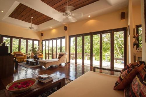 sala de estar con ventanas grandes y sofá en Villa Khao Phaengma, en Wang Nam Khiao