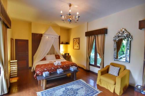 a bedroom with a bed and a chair and a chandelier at Villa Khao Phaengma in Wang Nam Khieo
