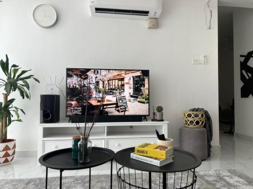 a living room with two tables and a flat screen tv at The Penthouse TROIKA KOTA BHARU in Kota Bharu