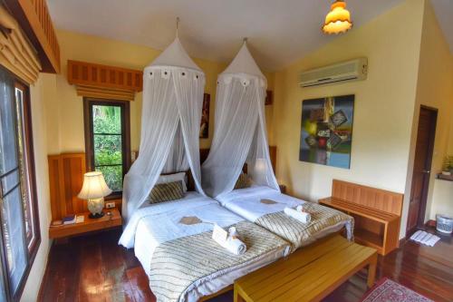 a bedroom with a large bed with mosquito nets at Villa Khao Phaengma in Wang Nam Khieo