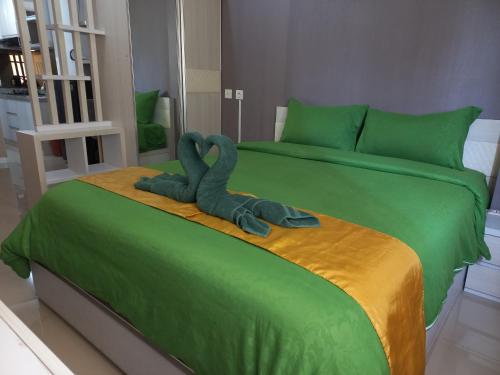 a green bed with a stuffed animal sitting on it at Nature's Room @ Aeropolis in Rawabambu
