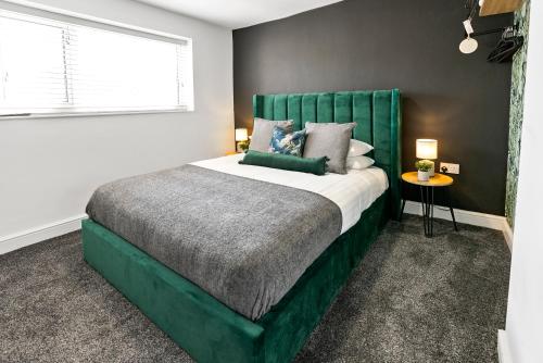 a bedroom with a large bed with a green headboard at The Treehouse at The Hideaway STAMP SA in Blackpool