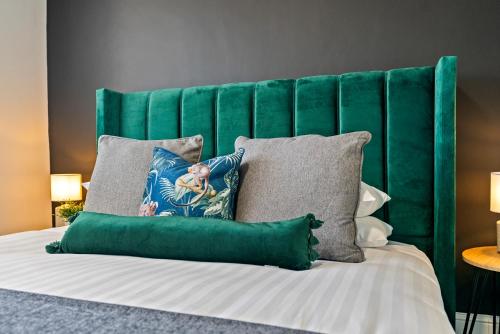 a bed with a green headboard and pillows at The Treehouse at The Hideaway STAMP SA in Blackpool
