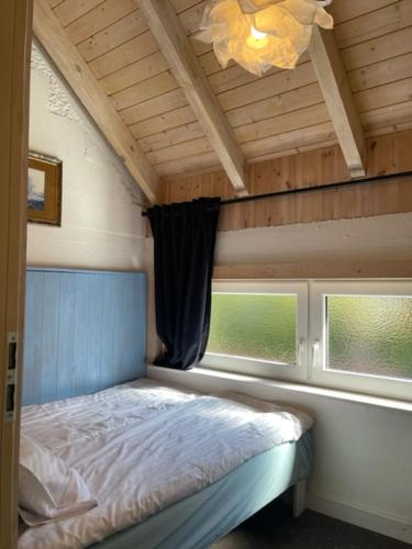 a small bedroom with a bed and two windows at Zagroda Dębki in Dębki