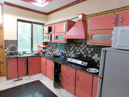 cocina con armarios rojos y nevera en Bhurban View Apartments, en Murree