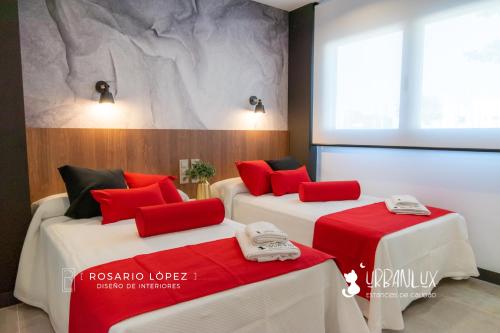 2 Betten mit roten Kissen in einem Zimmer in der Unterkunft Urbanlux Olimpia Sleep & More in Albacete
