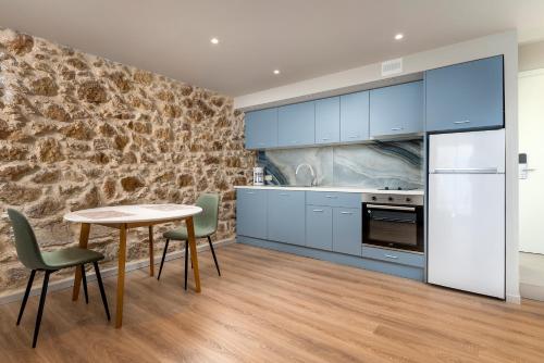 cocina con armarios azules, mesa y sillas en TheJoy Residence Apartments, en La Canea