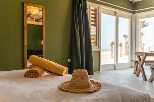 a straw hat and a towel sitting on a bed at Oasis212 Dakhla in Dakhla