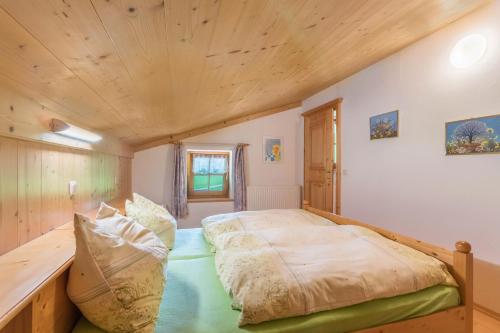 duże łóżko w pokoju z drewnianym sufitem w obiekcie Ferienwohnung Spielberg w mieście Sankt Martin bei Lofer