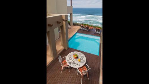a balcony with a table and chairs next to a swimming pool at Sea View 3 bedrooms Villa in Brenton On The Rocks in Brenton-on-Sea