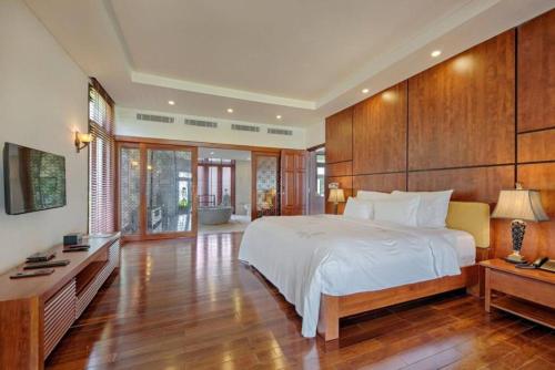 a bedroom with a large white bed and wooden walls at Da Nang Paradise Center My Khe Beach Resort & Spa in Da Nang