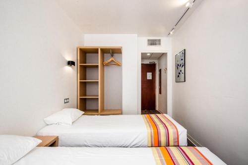 two beds in a room with white walls at Hôtel PB - Paris-Barcelone in Perpignan
