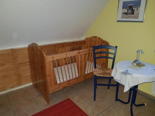 a room with a table and a chair and a crib at Haus Moewennest in Gelting