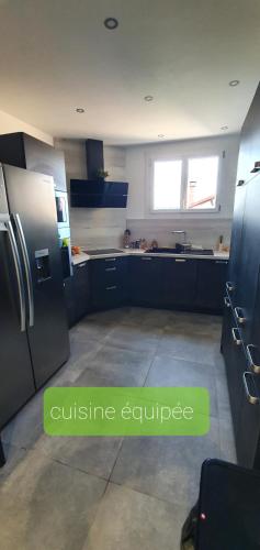 eine Küche mit blauen Schränken und einem Kühlschrank aus Edelstahl in der Unterkunft Agréable Villa pour 8 personnes in Pont-du-Château
