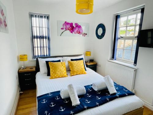 a bedroom with a bed with yellow and blue pillows at Captains Rest - 2 bedroom apartment in the heart of Brixham in Brixham