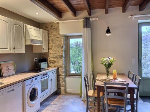 a kitchen with a table and a dining room at Maison chaleureuse en pierres apparentes in Le Pont Legé