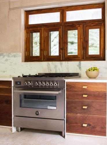 a kitchen with a stainless steel stove and wooden cabinets at Amaya Life Kasauli in Kasauli