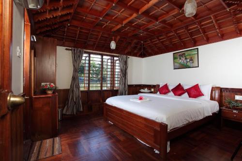 sypialnia z dużym łóżkiem z czerwonymi poduszkami w obiekcie Rajahamsam Houseboat w mieście Kumarakom