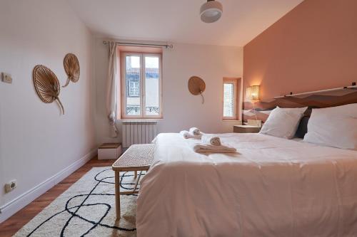 a bedroom with a large white bed with towels on it at La Cabane en Ville in Riom