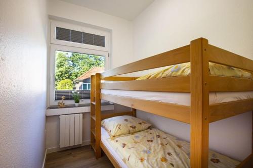 a bedroom with two bunk beds and a window at Wohnung Nr 2 im Wikingerhof in Altfunnixsiel