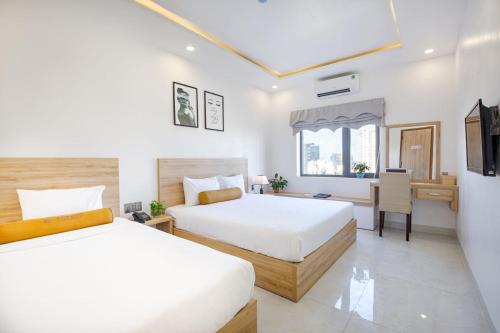 a bedroom with two beds and a desk and a table at Continent Apartment in Da Nang