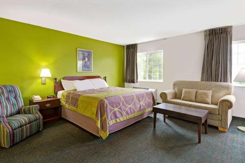 um quarto de hotel com uma cama e uma cadeira em Super 8 by Wyndham De Soto em De Soto
