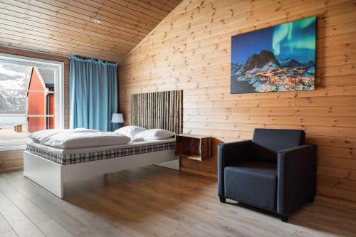 a bedroom with a bed and a chair at Eliassen Rorbuer in Reine