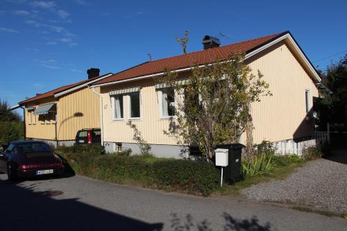 una casa amarilla con un coche aparcado delante de ella en Tallkrogen Romantic House - Upper or Lower Apartment, en Estocolmo