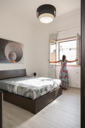 a woman is looking out the window of a bedroom at InCanti Salentini Apartments in Surbo