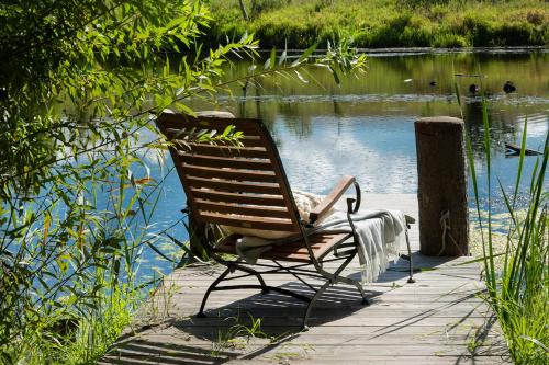 a rocking chair sitting on a dock near the water at Naturnahes, neu möbl.Apartment, hundefreundlich in Neu Gaarz