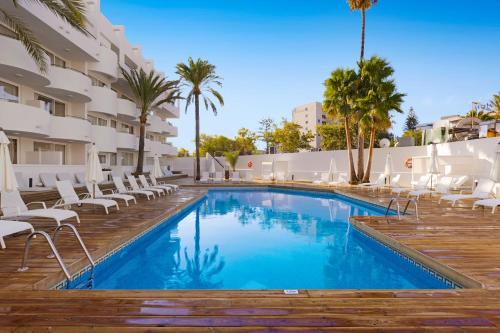 a pool at a hotel with chairs and palm trees at Palmanova Beach Apartments by TRH in Palmanova
