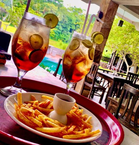 a plate of french fries and two drinks on a table at Villa Pinnawala in Pinnawala