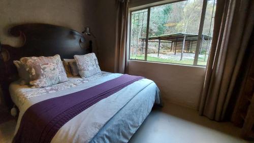 a bedroom with a bed with a large window at Lake House in Dullstroom