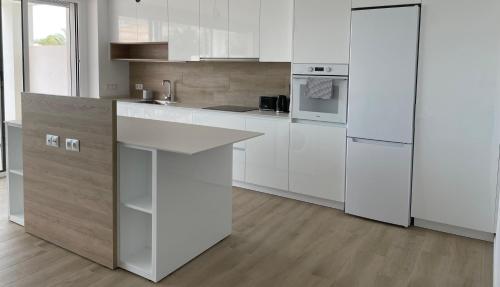 a white kitchen with white appliances and wooden floors at Oropesa del Mar, Playa Morro de Gos, Playa Blanca in Oropesa del Mar