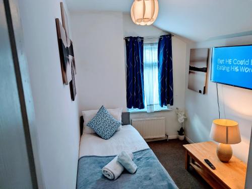 Cette petite chambre comprend un lit, une table et une télévision. dans l'établissement Gillings Villa -5 Bed Great For Long & Short Stay!!! Gillingham Kent, à Hoo