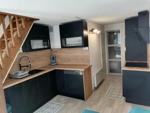 - une cuisine avec des placards noirs et un évier dans l'établissement Le Tetrao, aux Angles