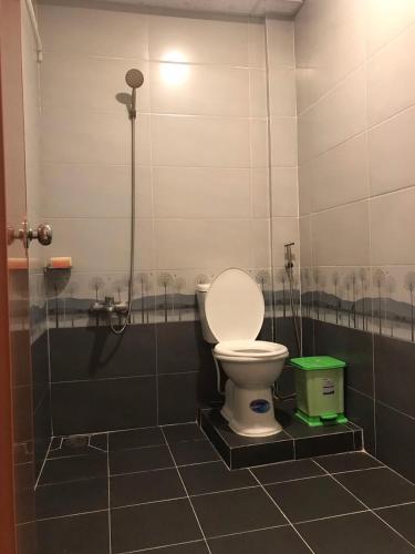 a bathroom with a toilet and a green trash can at Nam Thanh Homestay in Vĩnh Long
